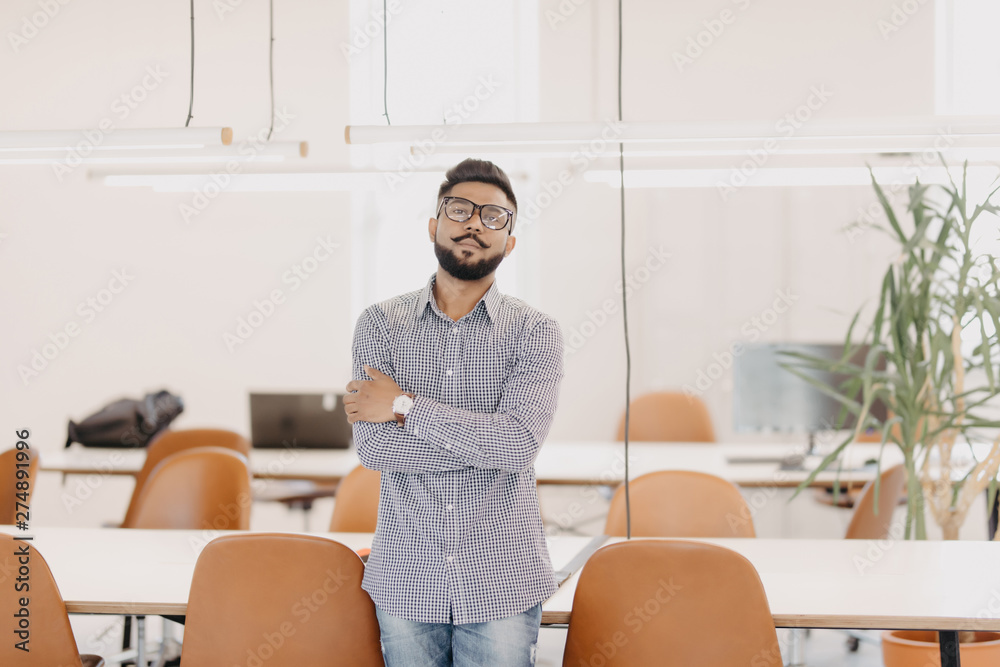 Young happy indian business man standing in modern office Young happy indian business man standing in modern office