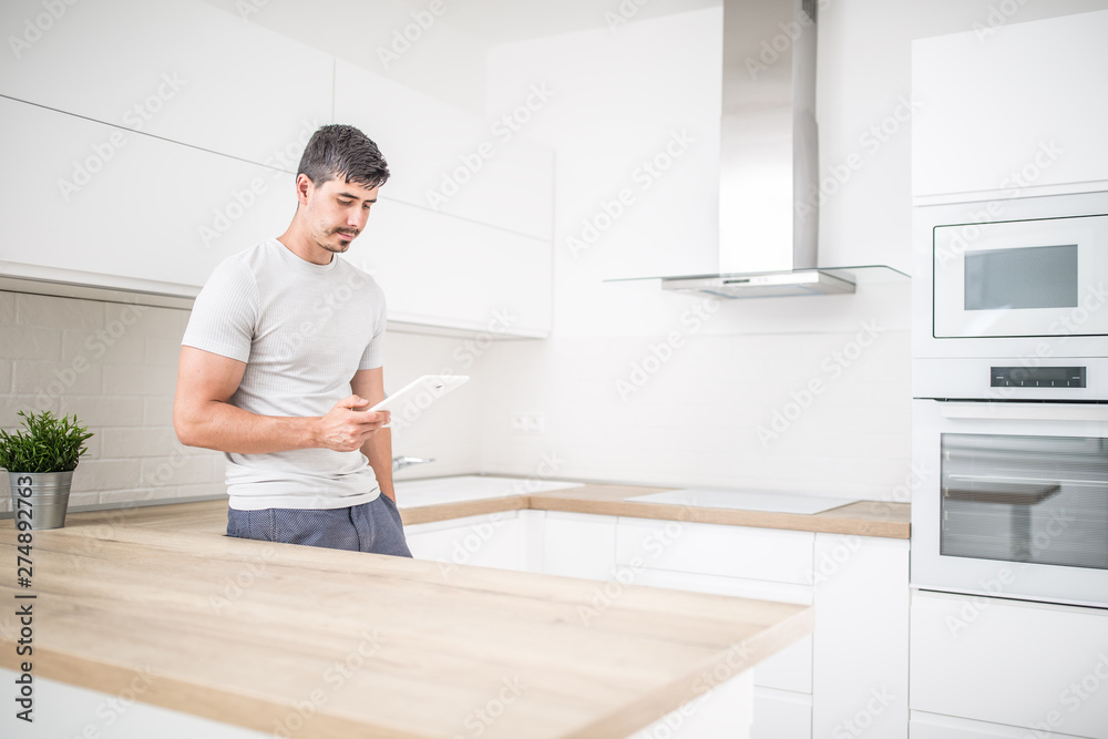 Young man in home kitchen with tablet Young man in home kitchen with tablet
