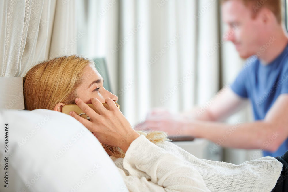 Pretty young woman lying in bed and talking on phone with friend Pretty young woman lying in bed and talking on phone with friend