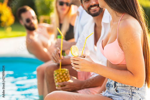 Friends drinking cocktails by the pool