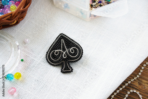 Handmade beaded brooch  Spades black on table on white background