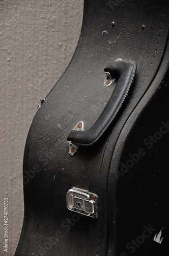 Close up of an old guitar case against a wall
