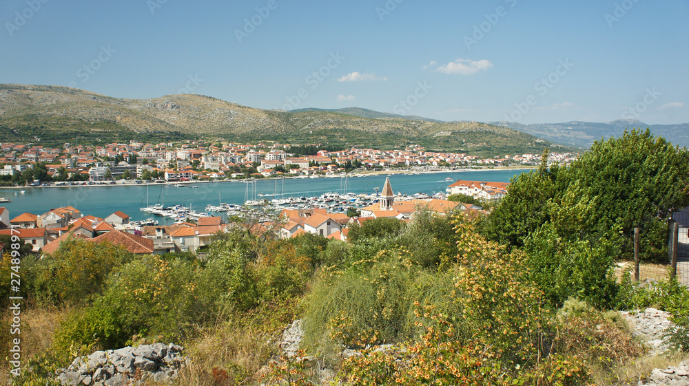 Obraz premium Scenic view of the city with mountain background, beautiful cityscape with houses, sunny day, Trogir, Dalmatia, Croatia