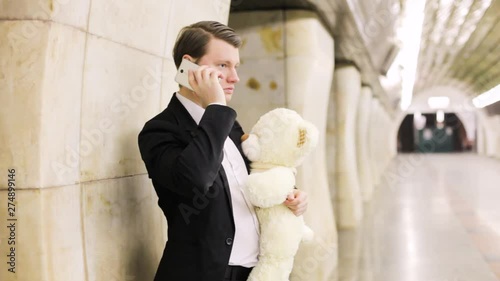 Man talking on the phone with his beloved, in his hand a gift is a toy bear. photo