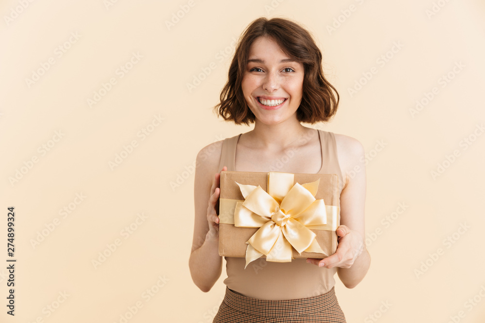 Portrait of attractive caucasian woman 20s dressed in casual clothes smiling at camera while holding present box Portrait of attractive caucasian woman 20s dressed in casual clothes smiling at camera while holding present box