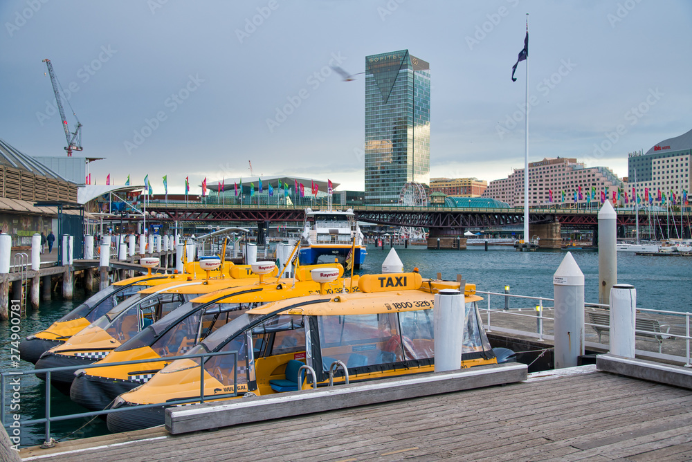 Obraz premium SYDNEY - AUGUST 18, 2018: Water Taxis in Darling Harbor on a beautiful day. Sydney attracts 20 million tourists annually