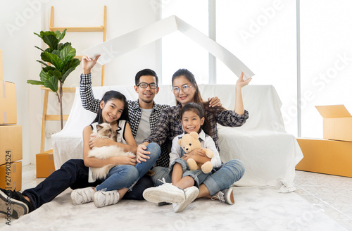 Happy Asian male and female Sitting On Floor Do gestures protection, take care children together. young Asian family team mother, father and kids in new home. concept Starting a family life, moving