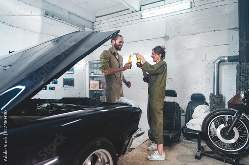 Caucasian couple hanging out in a garage, fixing an old retro vintage car © supamotion