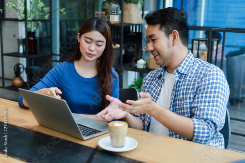 Wallpaper Mural Asian couple in blue shirt drinking coffee talking and working with computer laptop smile and  happy mood in coffee shop cafe Torontodigital.ca