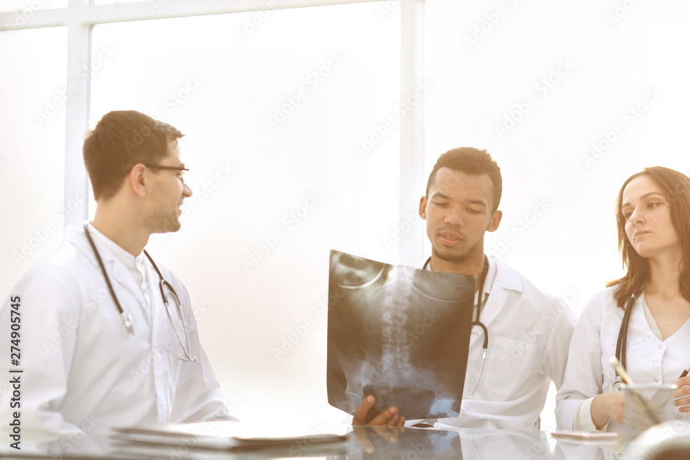 doctors discuss the x-ray of the patient sitting at the table