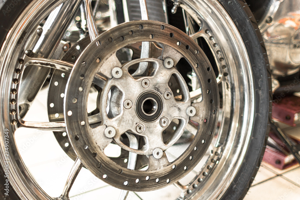 Wheel rim. A disk on a motorcycle wheel. Chrome part. Biker background. Part of a cruiser close-up. Two-wheeled transport. The design of the mechanism. Heavy machinery.