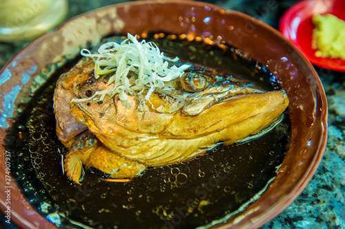 Japanese food concept. Salmon head steamed with sweet sauce and vegetable in Japanese style. Salmon kabutoni steamed, Japanese food style. Salmon head boiled in soy sauce with vegetables.  photo