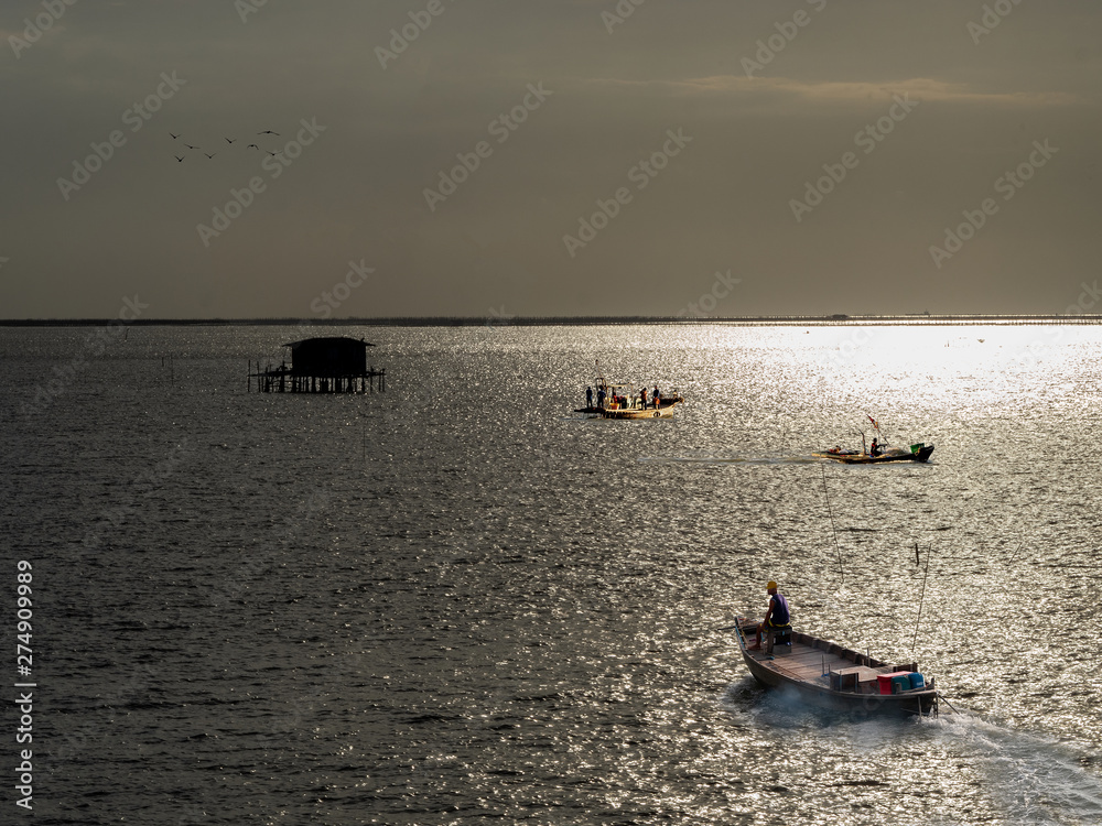 Coastal fishing boats are sailing on sunset at the bay of Bangsaen, Thailand.