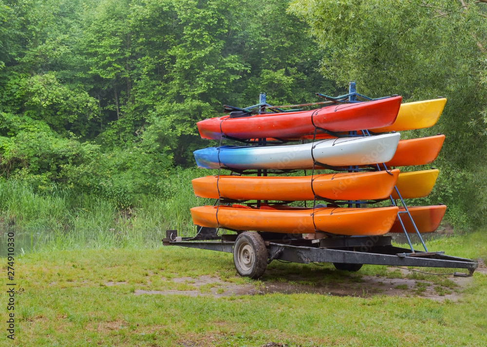 Kayaks by car delivered to the river. On the trailer with eight canoes.