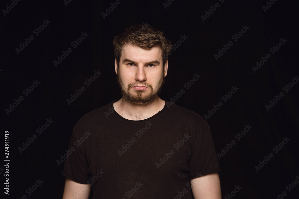 Close up portrait of young caucasian man isolated on black studio background. Photoshot of real emotions of male model. Mourning, mental suffering. Facial expression, human nature and emotions concept