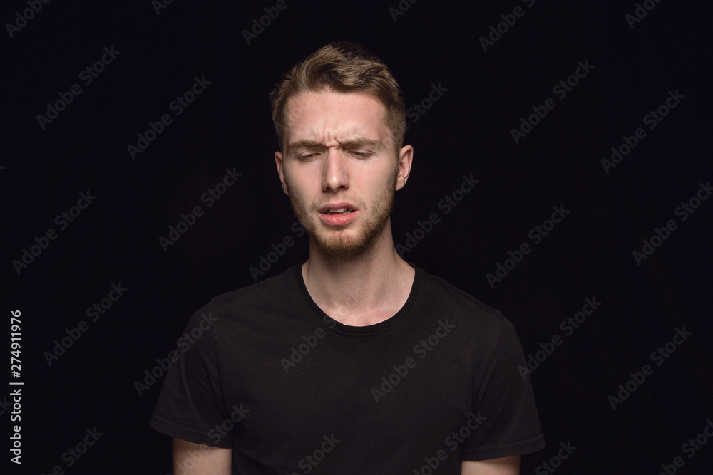 Close up portrait of young caucasian man isolated on black studio background. Photoshot of real emotions of male model. Mourning, mental suffering. Facial expression, human nature and emotions concept Close up portrait of young caucasian man isolated on black studio background. Photoshot of real emotions of male model. Mourning, mental suffering. Facial expression, human nature and emotions concept