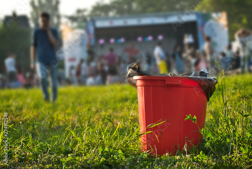 Red litter on green grass. Garbage in the nature after the concert. photo