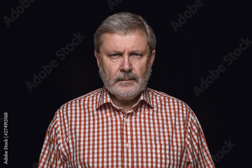 Close up portrait of senior caucasian man isolated on black studio background. Photoshot of real emotions of male model. Mourning, mental suffering. Facial expression, human nature and emotions