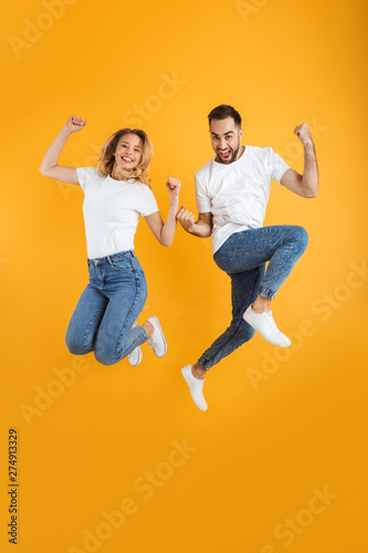Full length image of happy couple rejoicing and jumping while clenching fists together