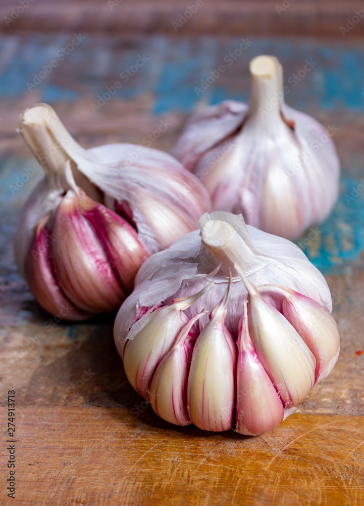 Obraz premium Three bulbs of fresh violet French garlic close up