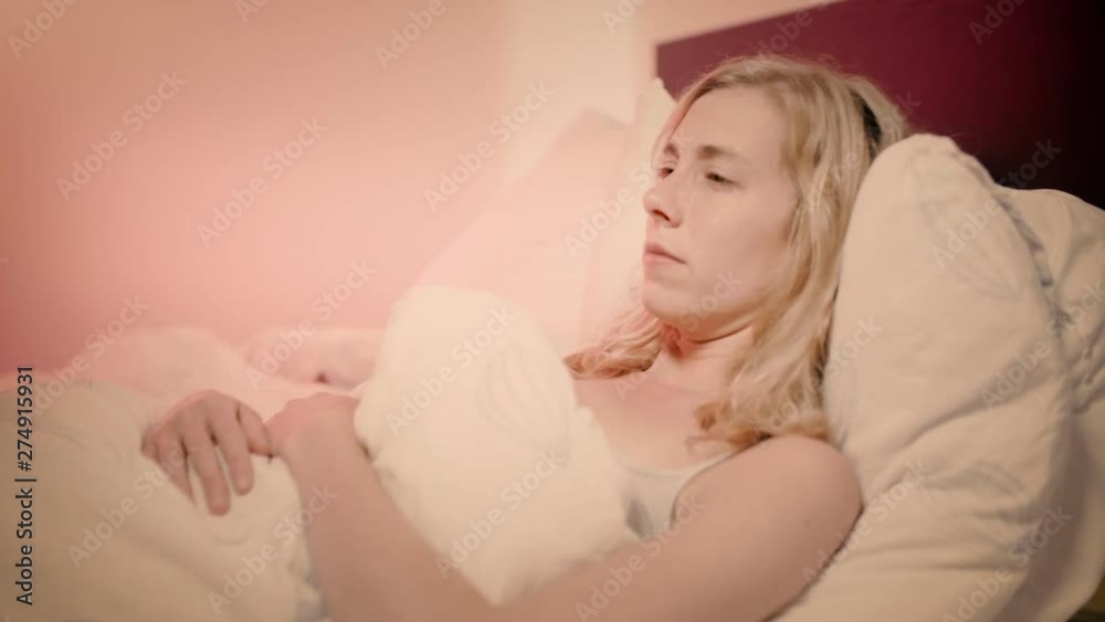 Woman in bed with a stomach ache rubbing her tummy Woman in bed with a stomach ache rubbing her tummy