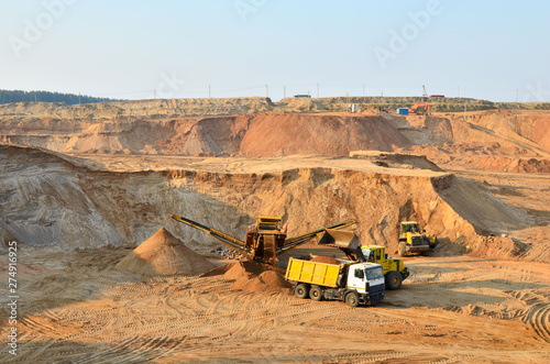 Wheel front-end loader unloading sand into heavy dump truck. Crushing plants, machines and equipment for crushing, grinding stone, sorting sand and bulk materials.