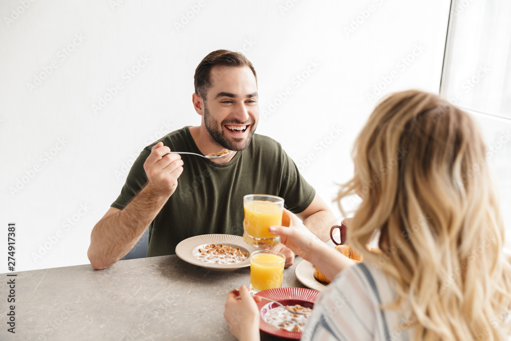 Happy young loving couple posing at the kitchen at home have a breakfast. Happy young loving couple posing at the kitchen at home have a breakfast.