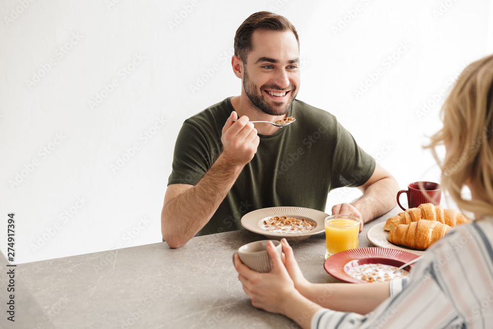 Happy young loving couple posing at the kitchen at home have a breakfast. Happy young loving couple posing at the kitchen at home have a breakfast.