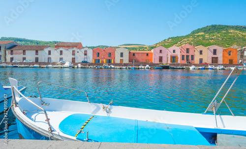 Panorama of the colorful town of Bosa along a river and hills in sunlight in spring