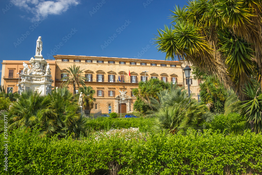 Wide beautiful view of famous Norman palace in Palermo Sicily, green garden with palms, historic statues and royal palace