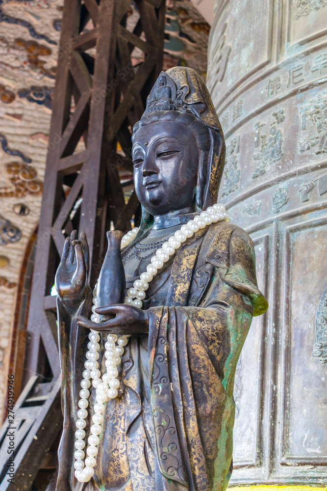 Ancient bronze statue with beads of pearls in temple Ancient bronze statue with beads of pearls in temple