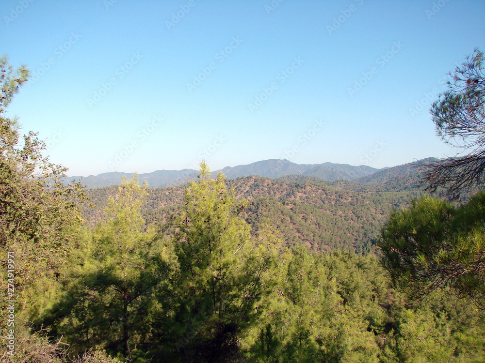 Panorama of low mountain ridges covered by green forest under the rays of autumn sunrise on the background of pure blue sky. Panorama of low mountain ridges covered by green forest under the rays of autumn sunrise on the background of pure blue sky.
