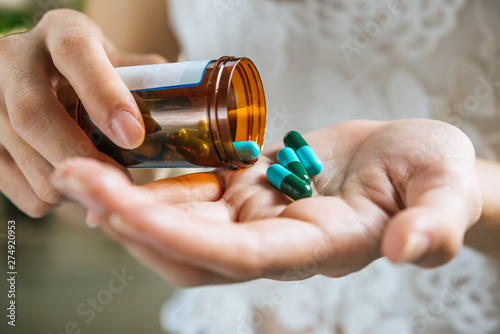 Woman's hand pours the medicine pills out of the bottle