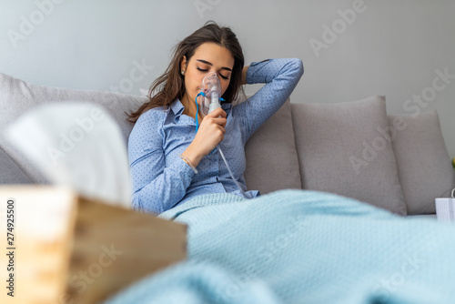 Obraz na plátně Woman holding a mask nebulizer inhaling fumes spray the medication into your lungs sick patient