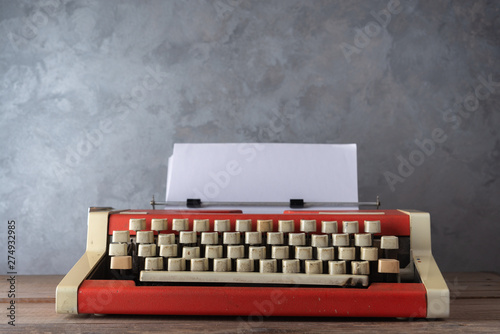 Old red typewriter on the table near the wall