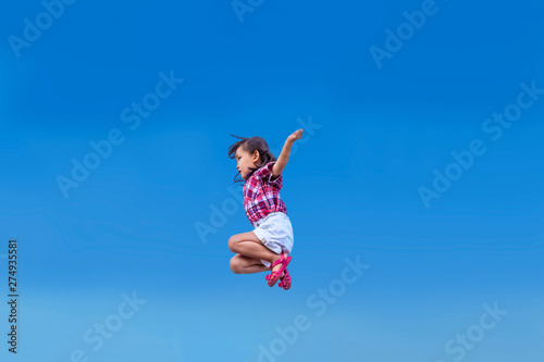 青空をバックにジャンプする幼い女の子。元気、パワフル、健康イメージ