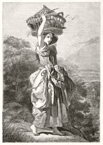 Obraz na plátně Beautiful female peasant with a long dress draping bounded on her hip holding a basket on her heads outdoor