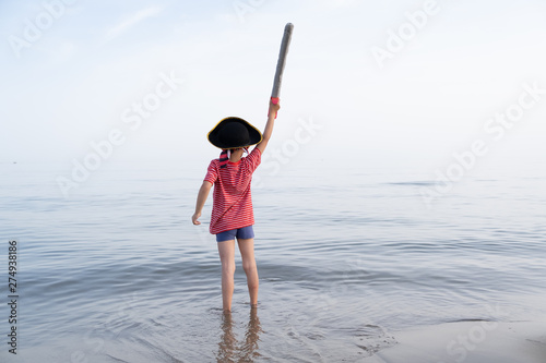 pirate child looks out to sea and shakes his sword up high