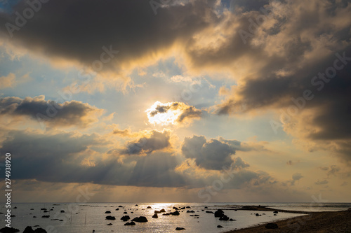 The sun light passes through the clouds at sunset.