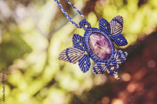 Macrame necklace with amethyst stone on natural background photo