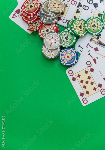 poker chips stack and playing cards on green table. empty space for text and design. top view