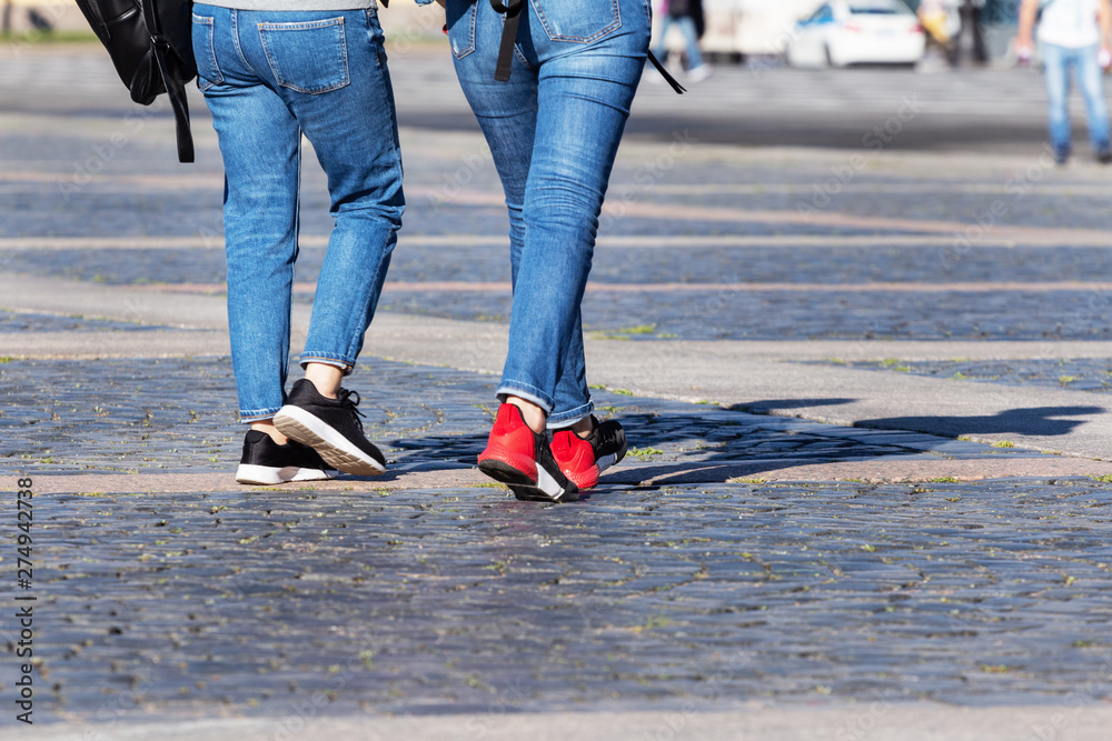 female legs in blue jeans and sneakers female legs in blue jeans and sneakers