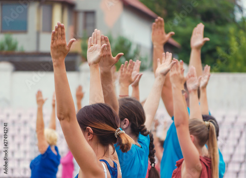raised hands of men and women for yoga training in the park
