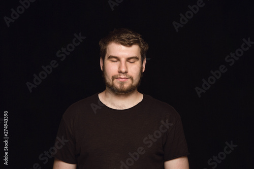 Close up portrait of young man isolated on black studio background. Photoshot of real emotions of male model with closed eyes. Thoughtful. Facial expression, human nature and emotions concept.