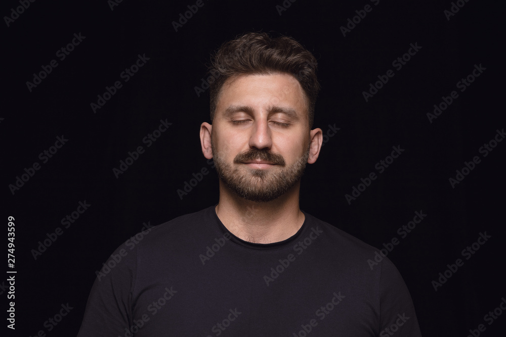 Close up portrait of young man isolated on black studio background. Photoshot of real emotions of male model with closed eyes. Thoughtful. Facial expression, human nature and emotions concept.