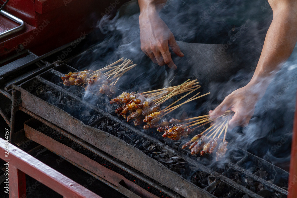 Chicken satay grill at a busy street food market Chicken satay grill at a busy street food market