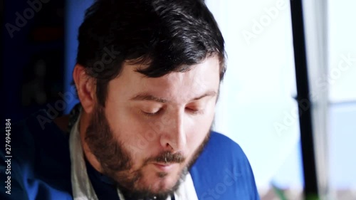 Happy smiling adalt man with beard eating a delicious french fries. Hungry young guy at cafe enjoys eating, chewing. Fast food restaurant concept. Close up photo