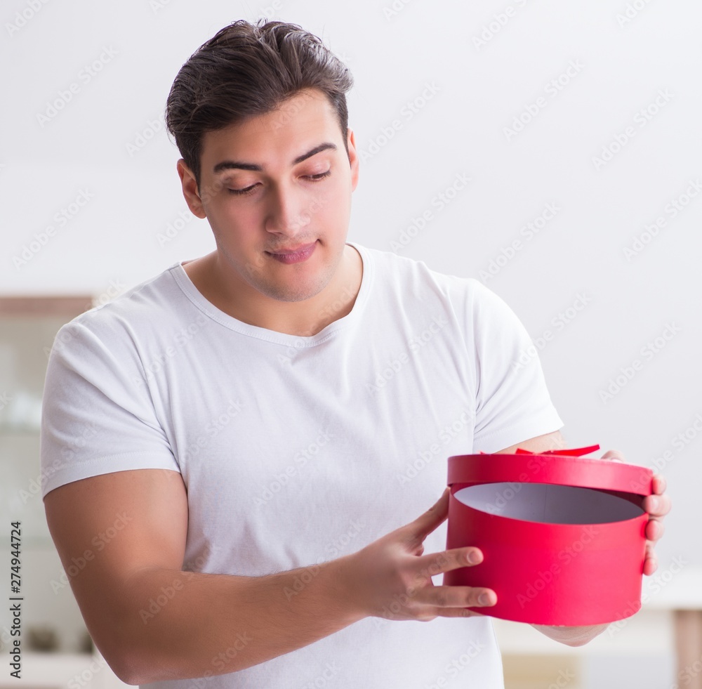 Young man with gift bag at home preparing suprise for wife Young man with gift bag at home preparing suprise for wife