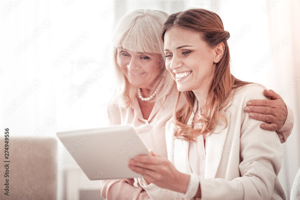 Two smiling happy women looking through the family pictures on a tablet Two smiling happy women looking through the family pictures on a tablet