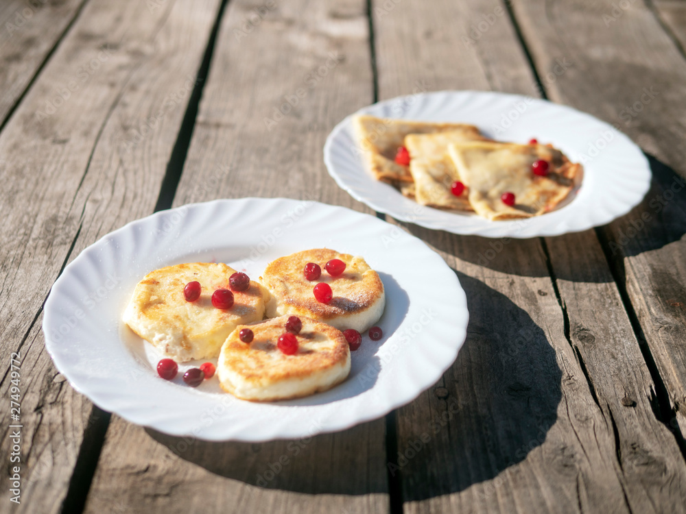 pancakes with wild berries on a white plate on a wooden background pancakes with wild berries on a white plate on a wooden background